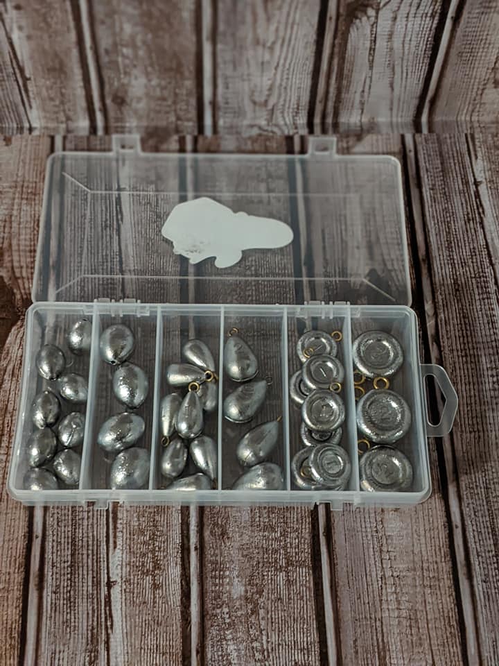 A plastic box filled with fishing weights is sitting on a wooden table.