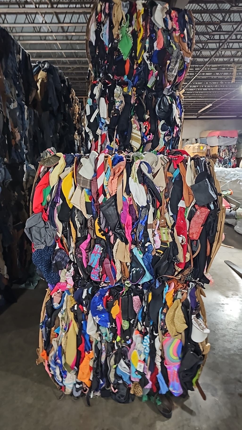 A large pile of clothes is stacked on top of each other in a warehouse.