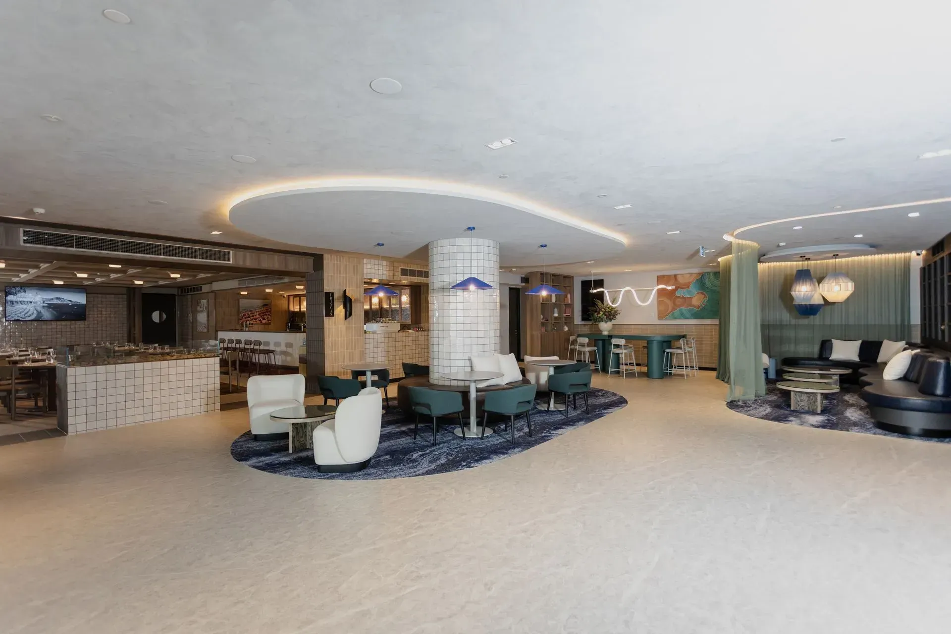 Modern hotel lobby with curved ceiling, seating areas, reception desk, and lounge lighting