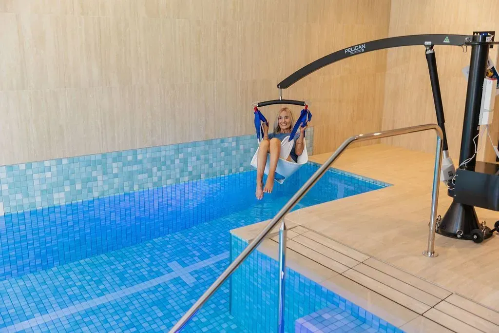 Person using a pool lift enters an indoor swimming pool.