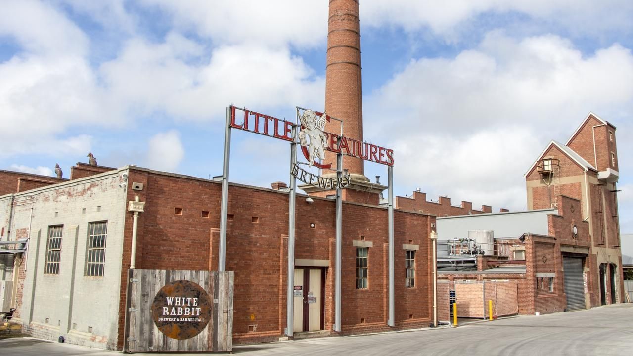Old brick industrial building with tall smokestack and faded sign under a cloudy sky