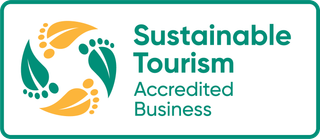 Sustainable Tourism Accredited Business logo with teal text and orange-green circular leaf emblem