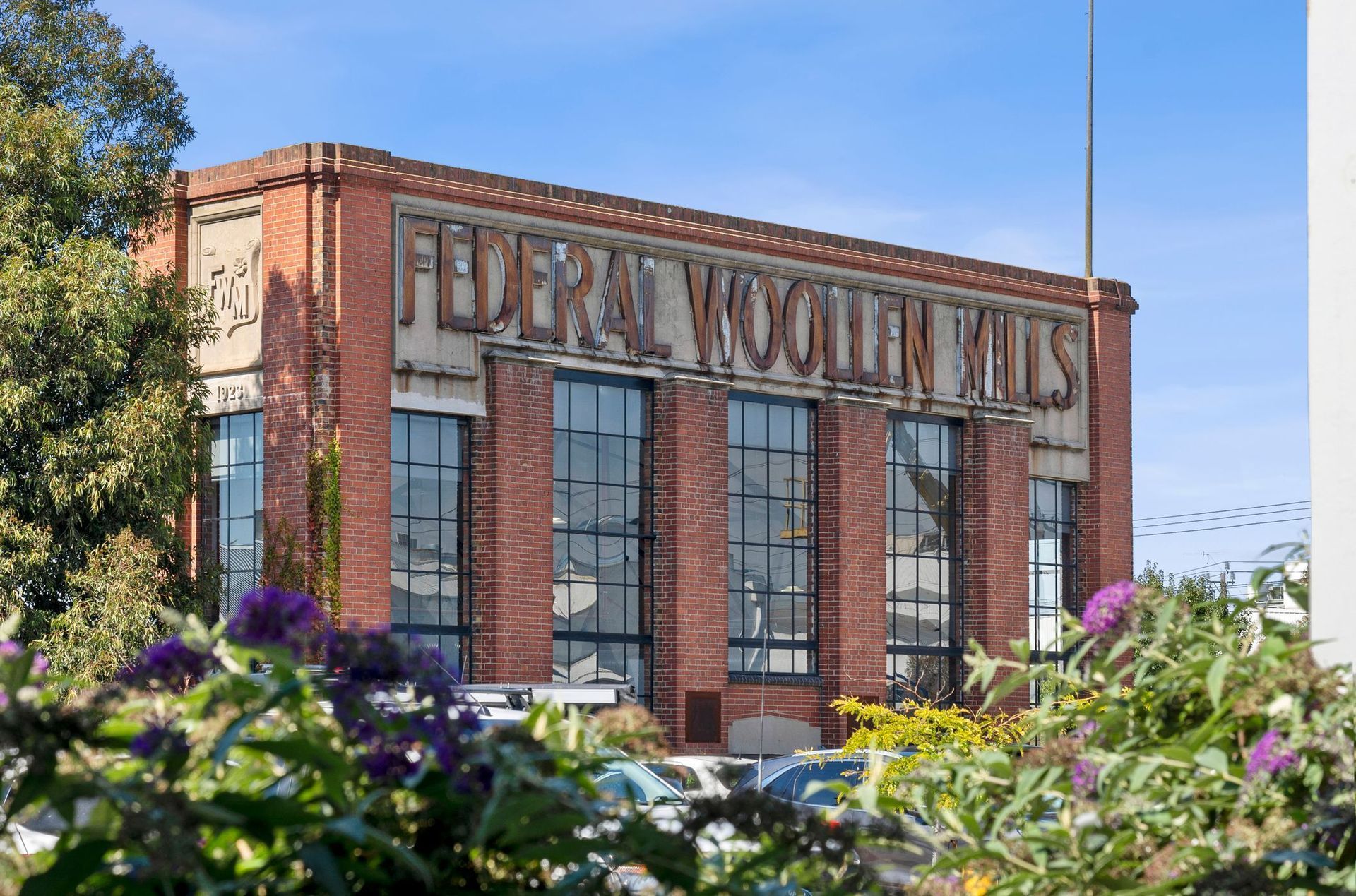 Bricks of a historic building framed by flowers and trees under a blue sky