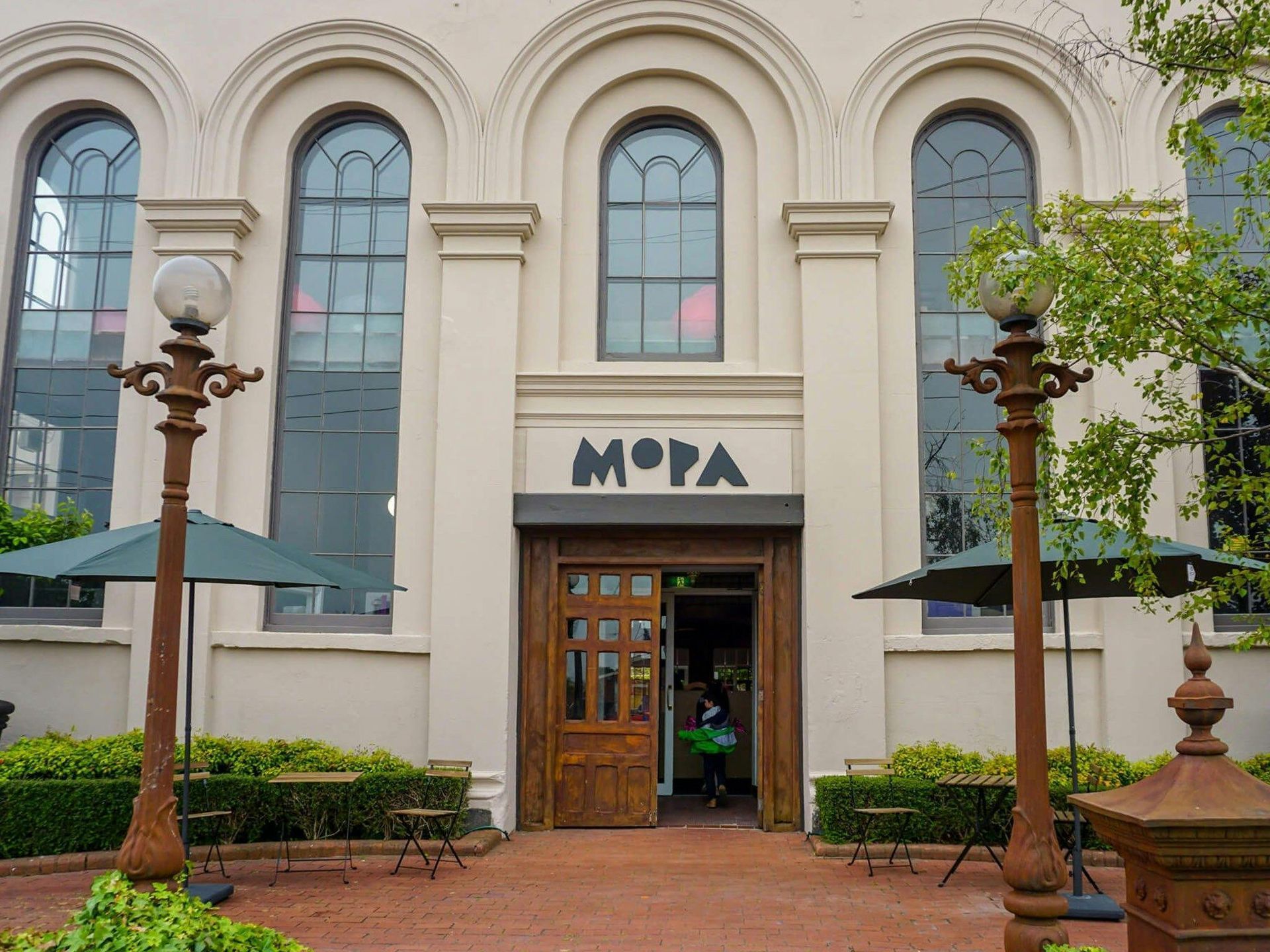 Museum entrance with arched windows, wooden doors, and decorative lampposts in front