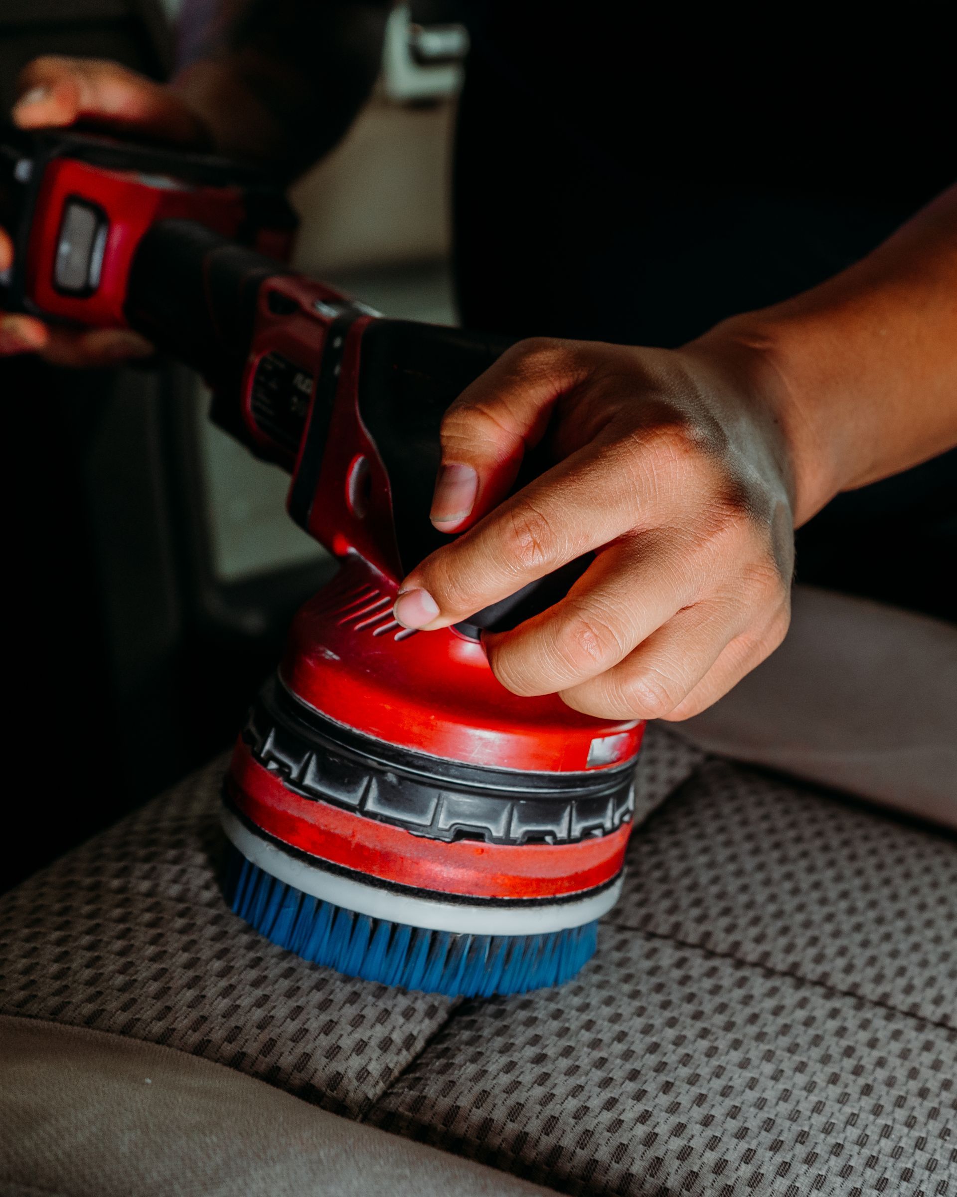 A person is cleaning a car seat with a brush.
