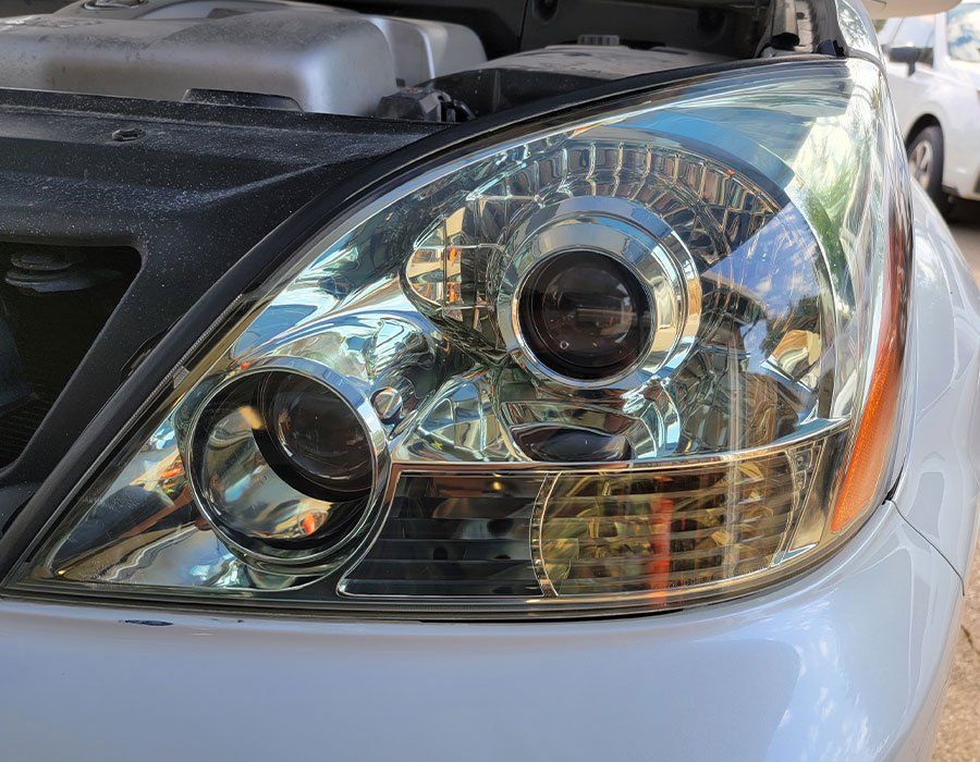 A close up of a car 's headlight with the hood open.