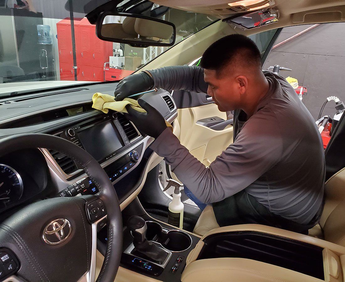 A man is cleaning the interior of a car with a cloth.