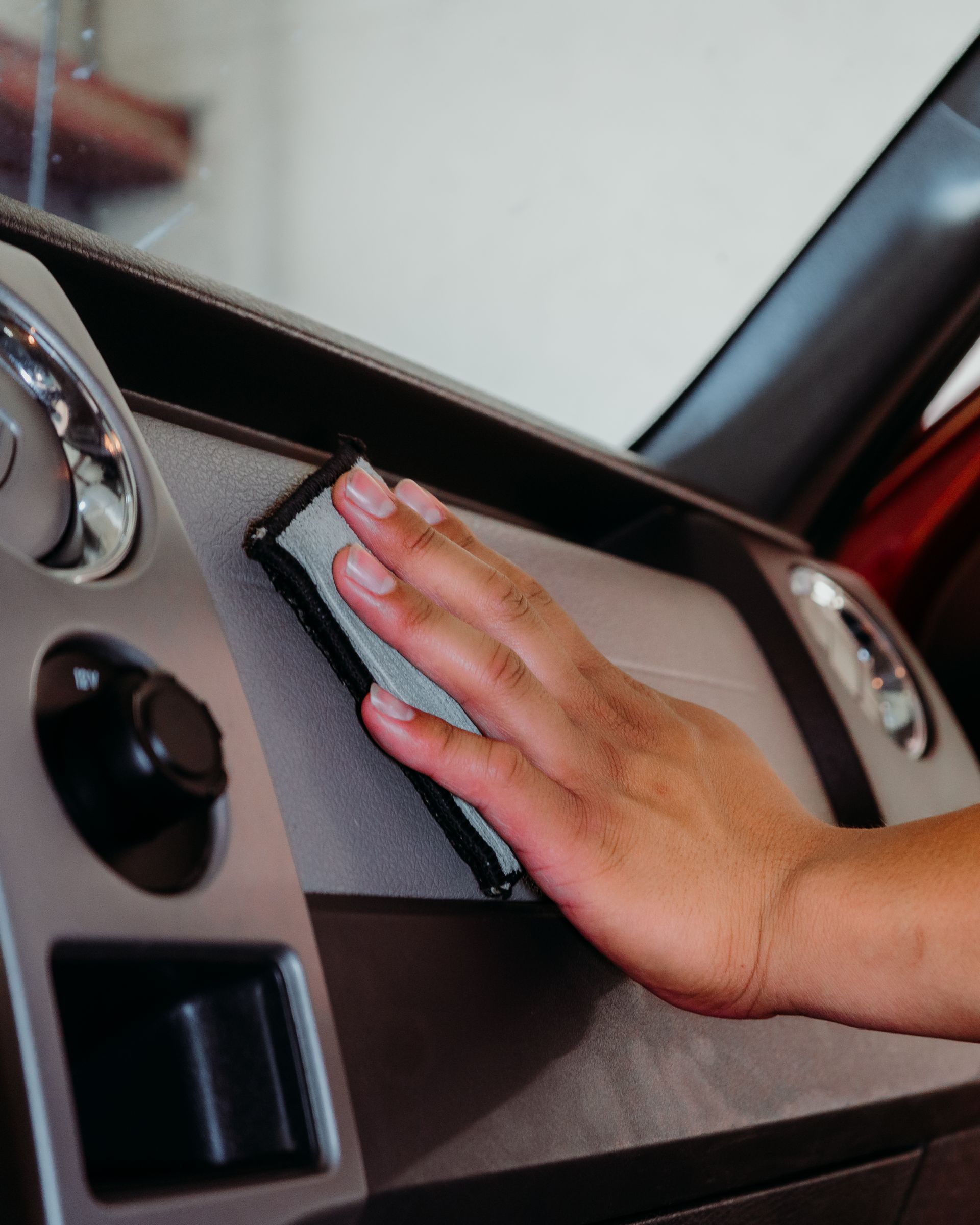 A person cleaning the dashboard of a car with a cloth