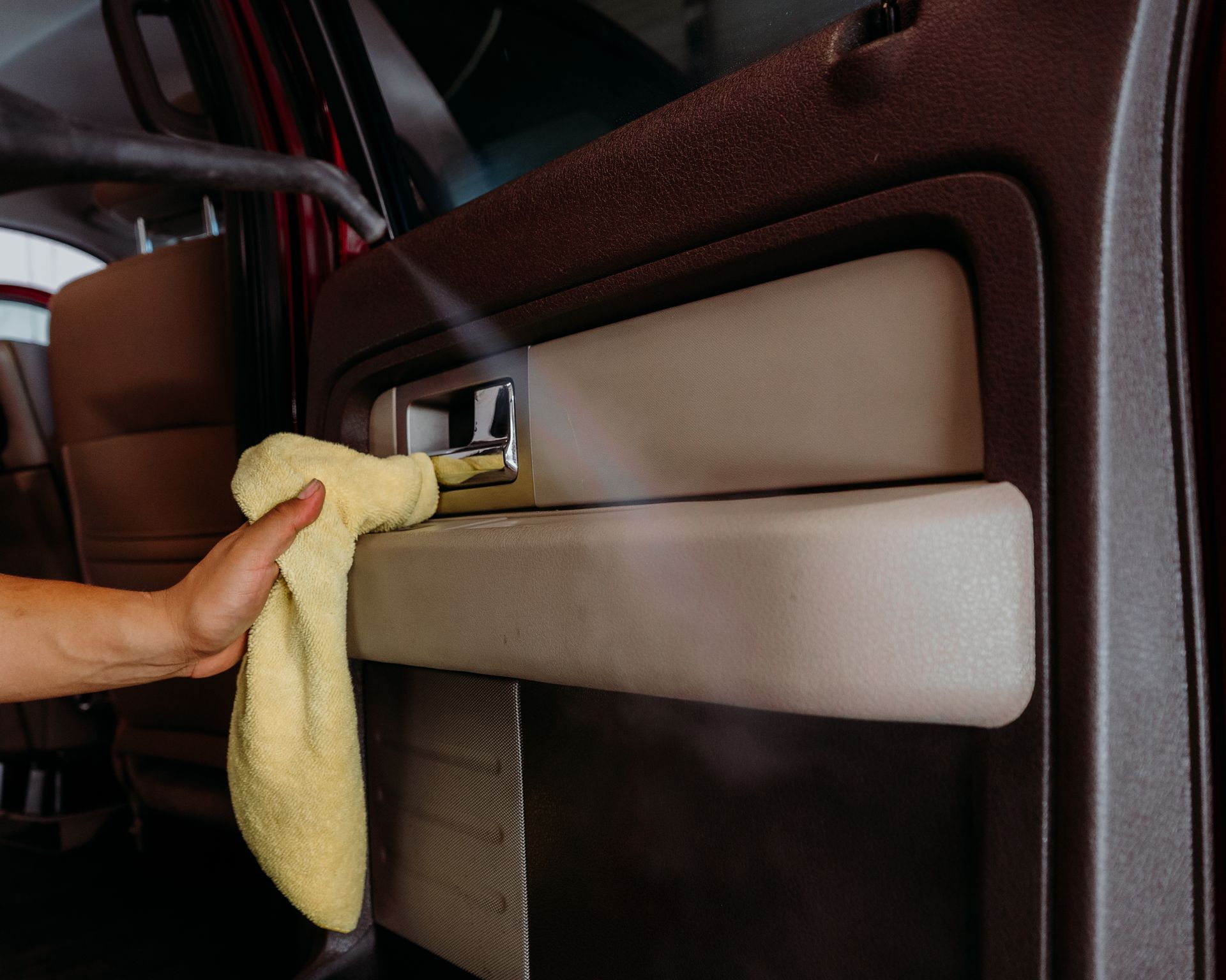 A person is cleaning a car door with a towel