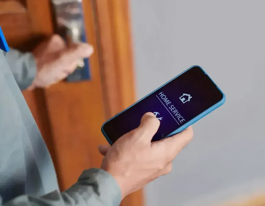 Person holding a smartphone with a dark screen and blue case in a doorway