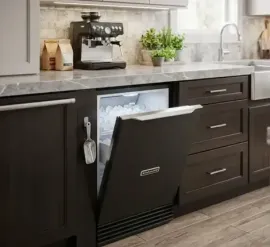 Modern kitchen with a pull-down dishwasher panel integrated into dark cabinets under a marble countertop.