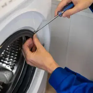 Person wiring an orange electrical component on a kitchen counter beside tools and a toolbox