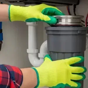 Person installing a kitchen garbage disposal under a sink with green-gloved hands