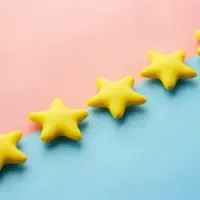 Five yellow star shapes on a pink and blue diagonal background