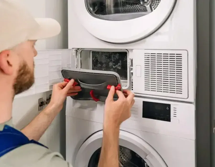 Worker repairing a front-loading dryer in a laundry room