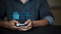 Person holding a smartphone with a holographic home automation interface overlay