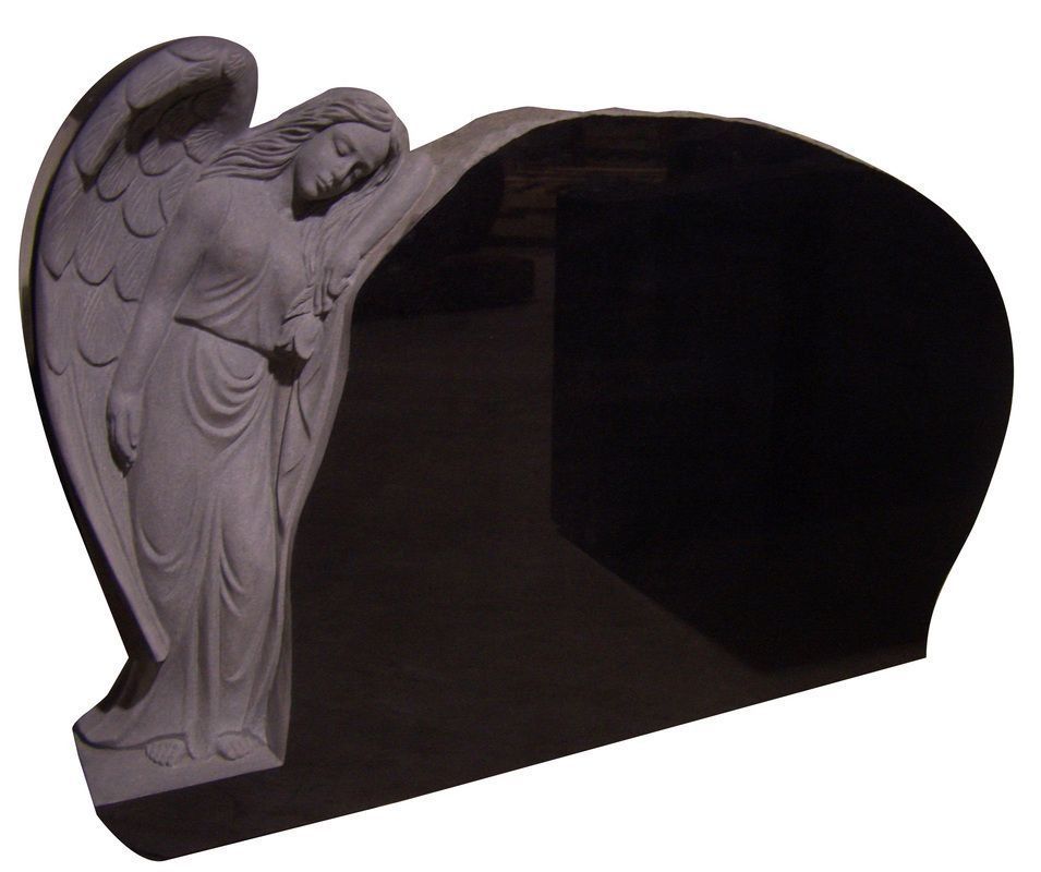 White angel statue beside a dark black arched memorial plaque or gravestone