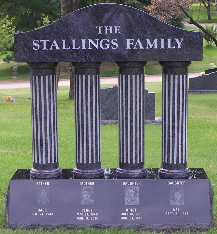 The Stallings Family memorial monument with four black columns in a grassy cemetery.