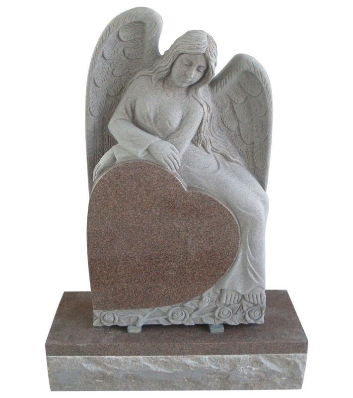 Gray angel statue seated behind a heart-shaped stone on a marble base
