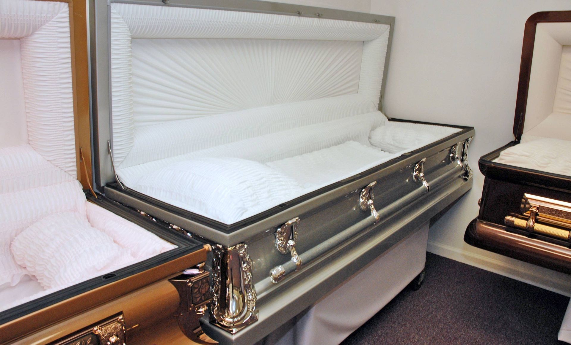 White coffin with satin lining and silver handles displayed in a showroom