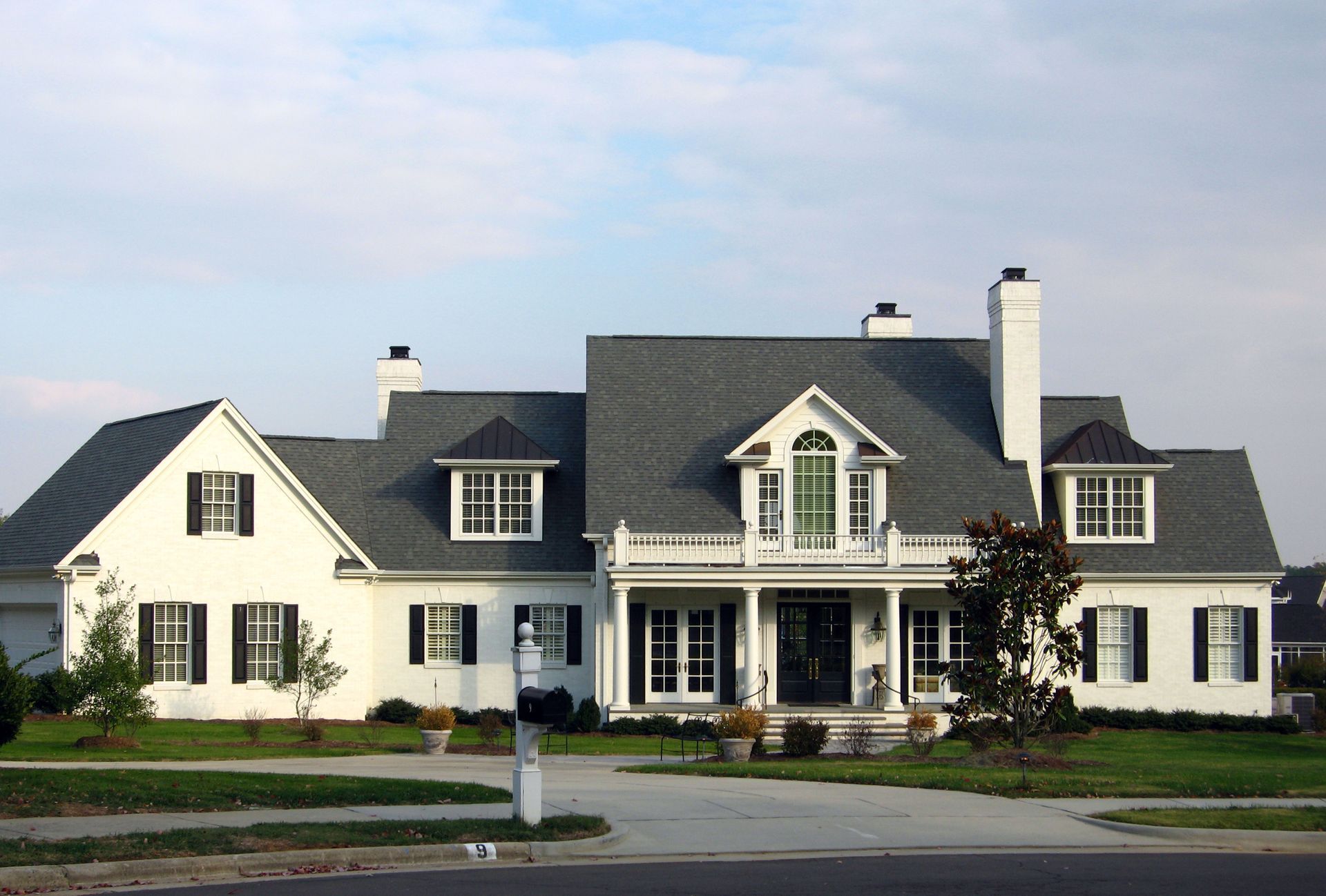 a large white brick house with a gray roof and black shutters
