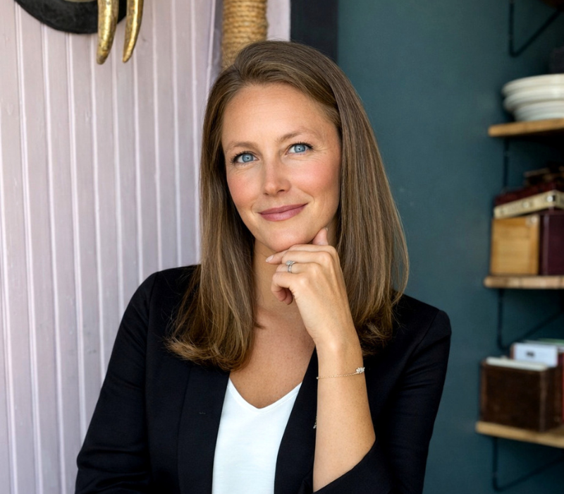 Portrait of a smiling woman in a black blazer leaning on her hand in a office