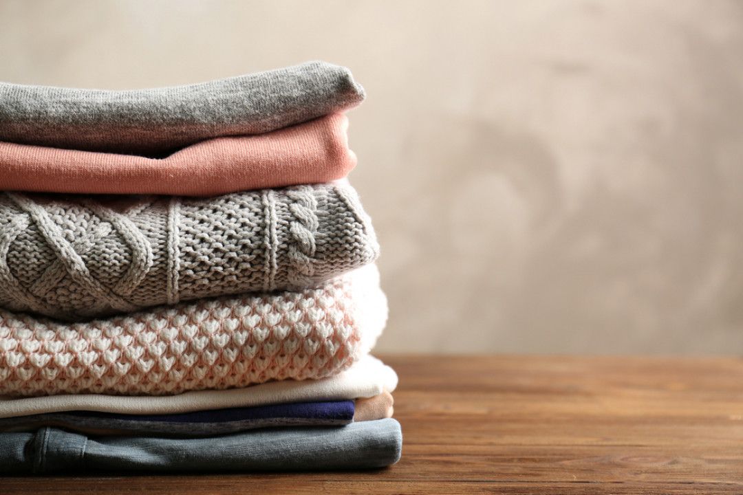 A pile of clothes is stacked on top of each other on a wooden table