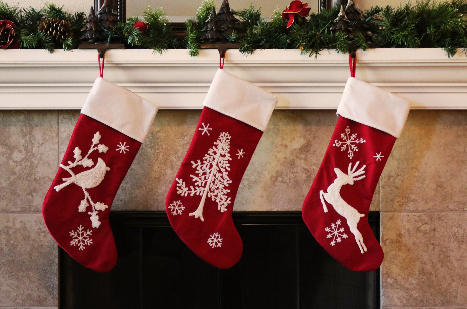 Three red and white christmas stockings hanging on a mantle