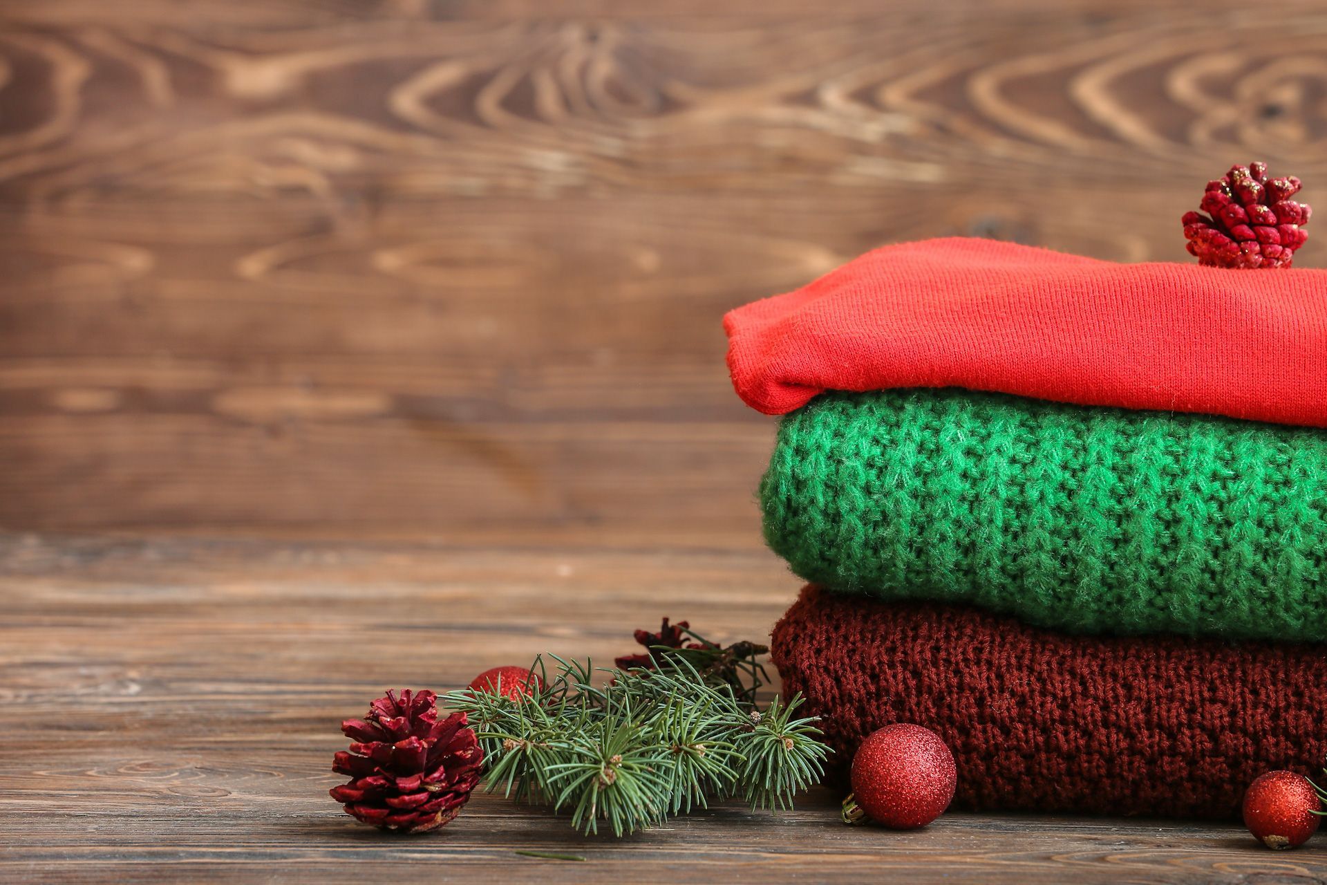 A stack of sweaters with christmas decorations on a wooden table