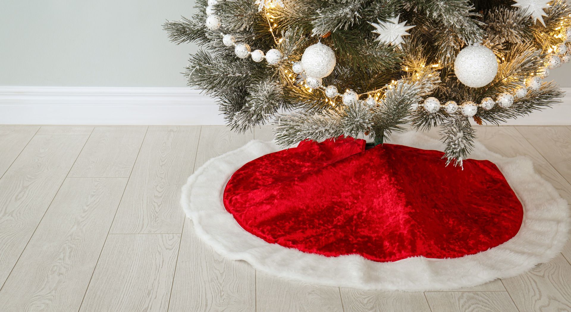 A christmas tree with a red and white skirt on the floor