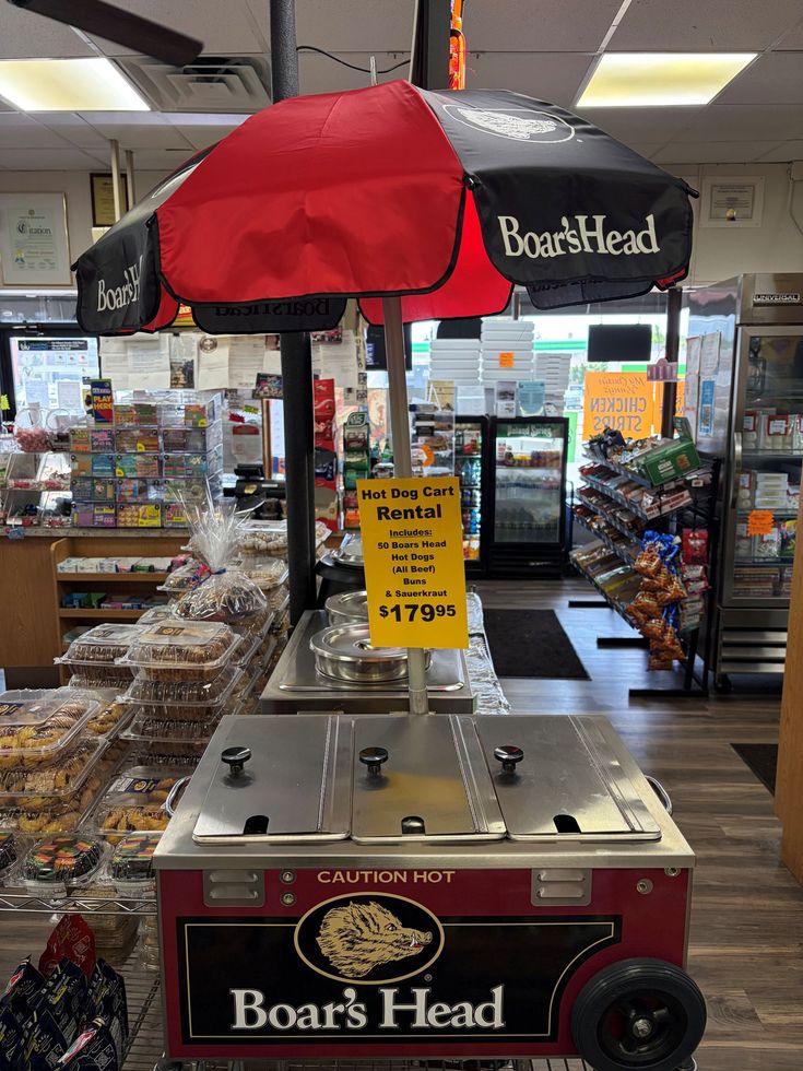 Boar’s Head deli display with red-and-black umbrella and packaged meats in a grocery store aisle