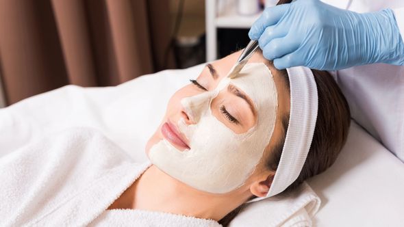 Una persona vestida con una bata blanca recibe un tratamiento facial profesional