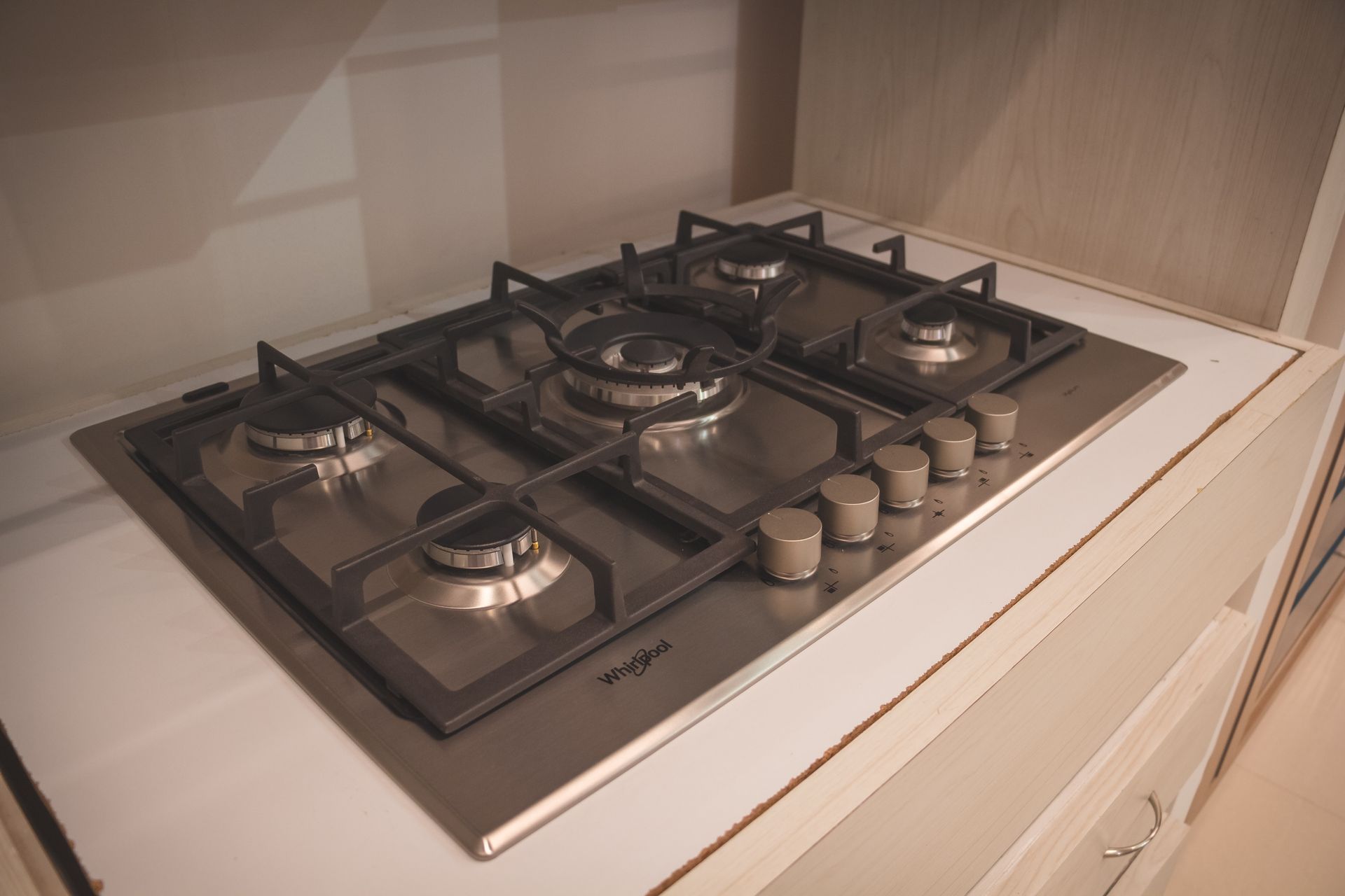Stainless steel gas stove top with five burners.