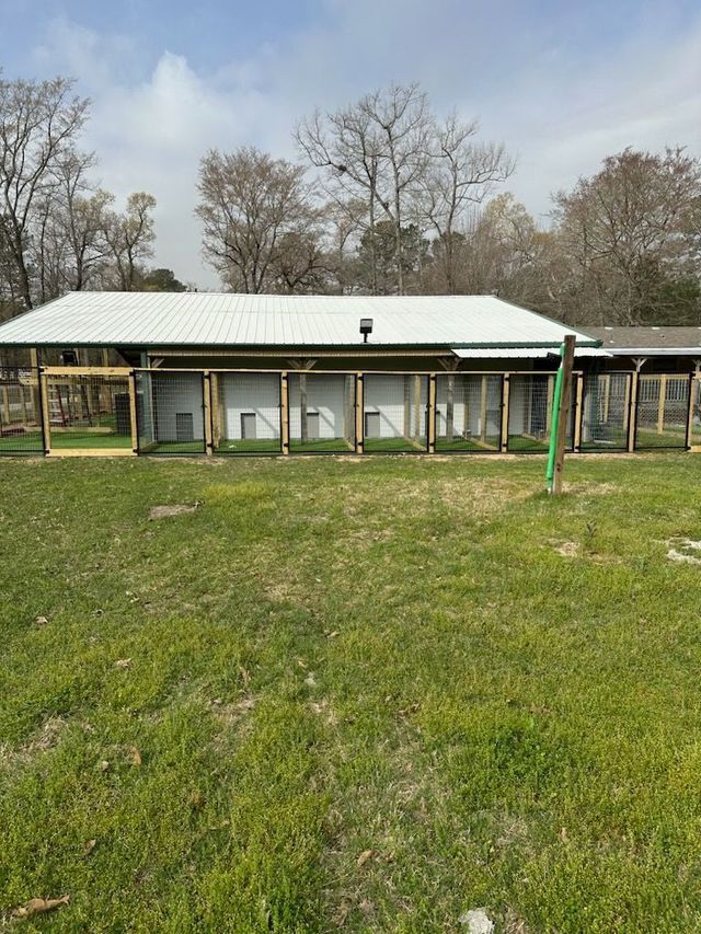 A large house with a lot of windows is sitting in the middle of a grassy field.