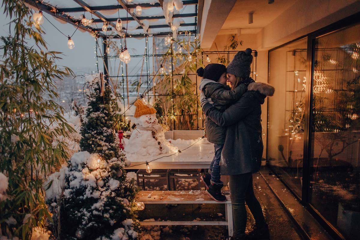 A man and a child are hugging on a balcony decorated for christmas