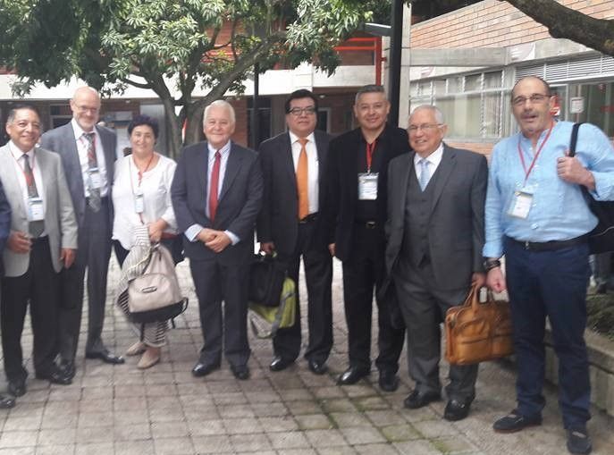 Grupo de personas vestidas con ropa de negocios de pie al aire libre en una acera, posando juntas con cordones y bolsos.