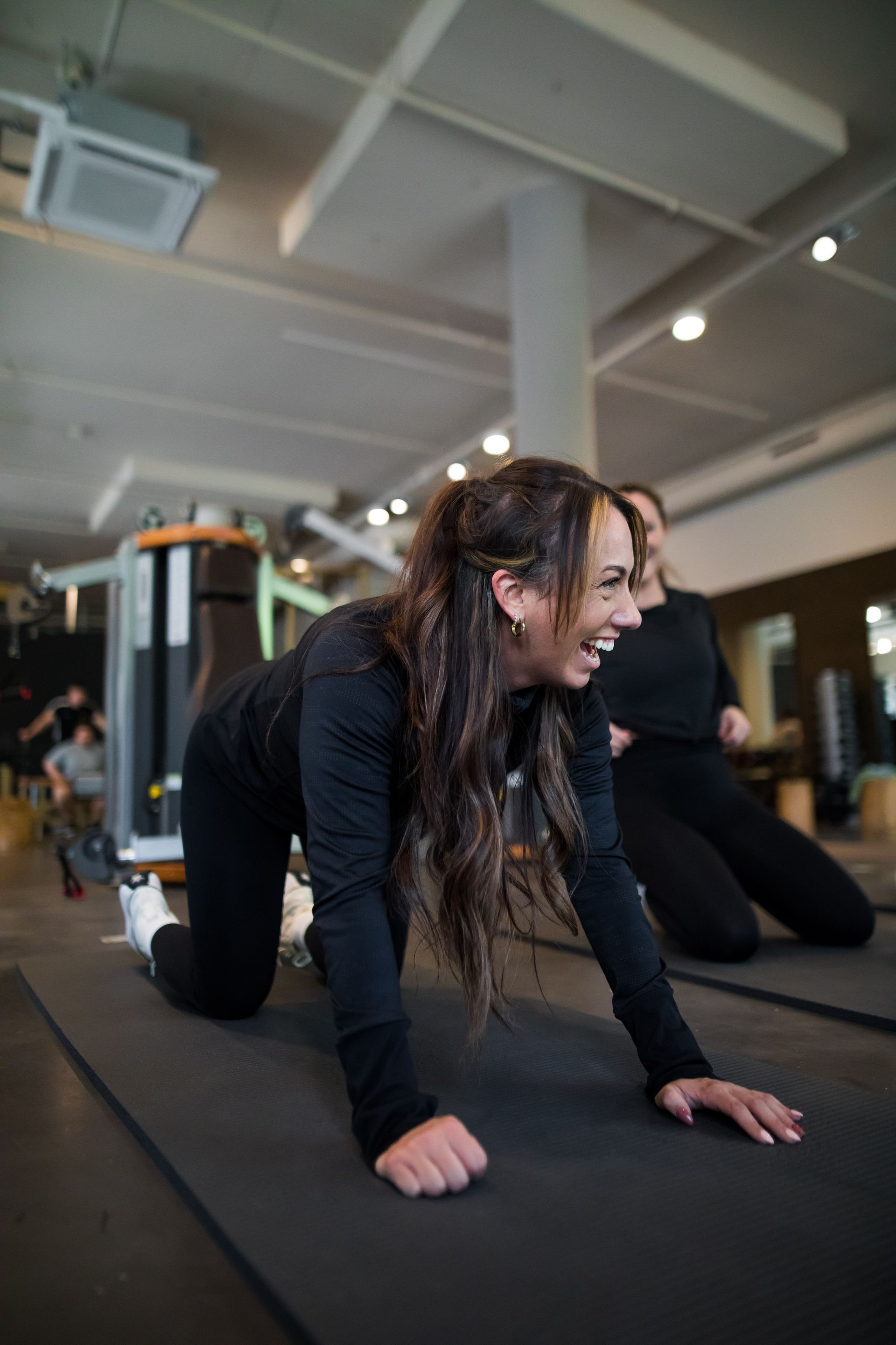 Een vrouw knielt op een yogamat in een sportschool.