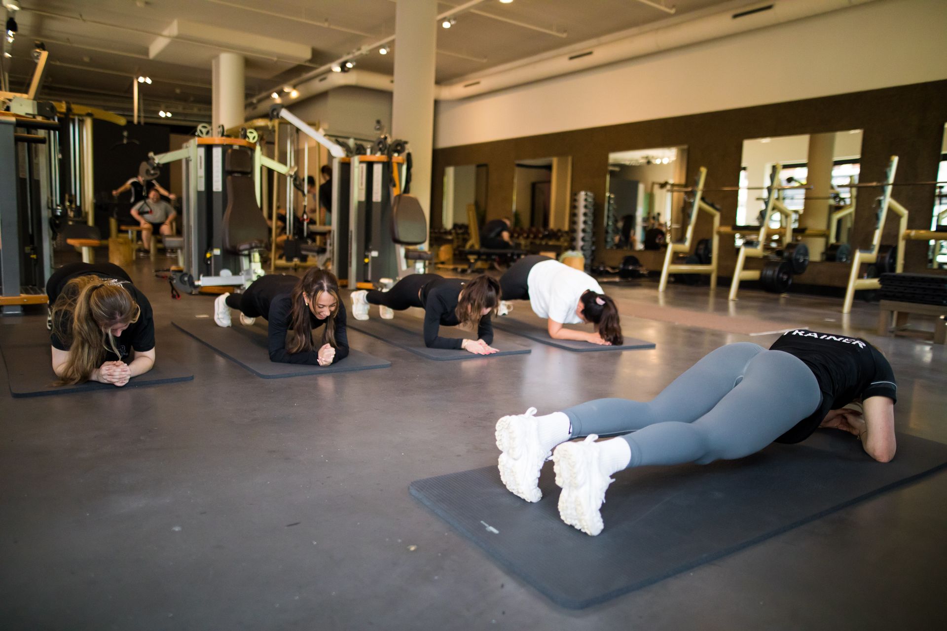 Een groep vrouwen doet push-ups op yogamatten in een sportschool.