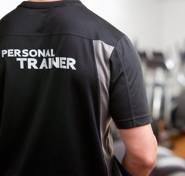 Een man die een zwart shirt draagt ​​met de tekst personal trainer op de achterkant