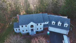 A brown house with a gray roof and white trim