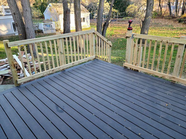 Fresh deck with light railings overlooking a wooded yard in autumn.