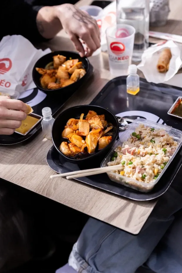 Tranches de thon poêlées aux graines de sésame, sauce, gingembre, citron et wasabi, servies sur une assiette noire.
