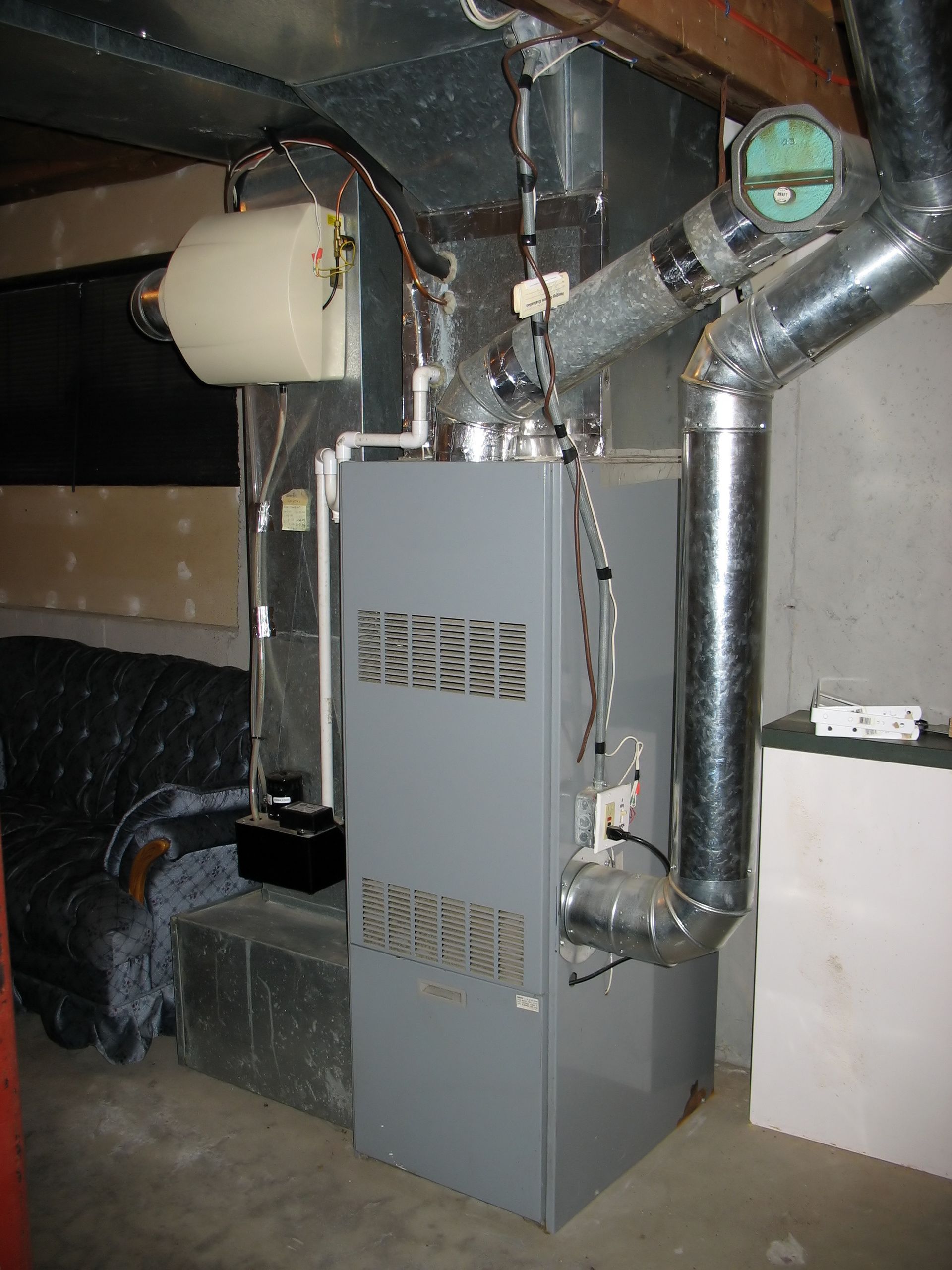 HVAC system in an attic. Gray and silver components with electrical wiring and ductwork.