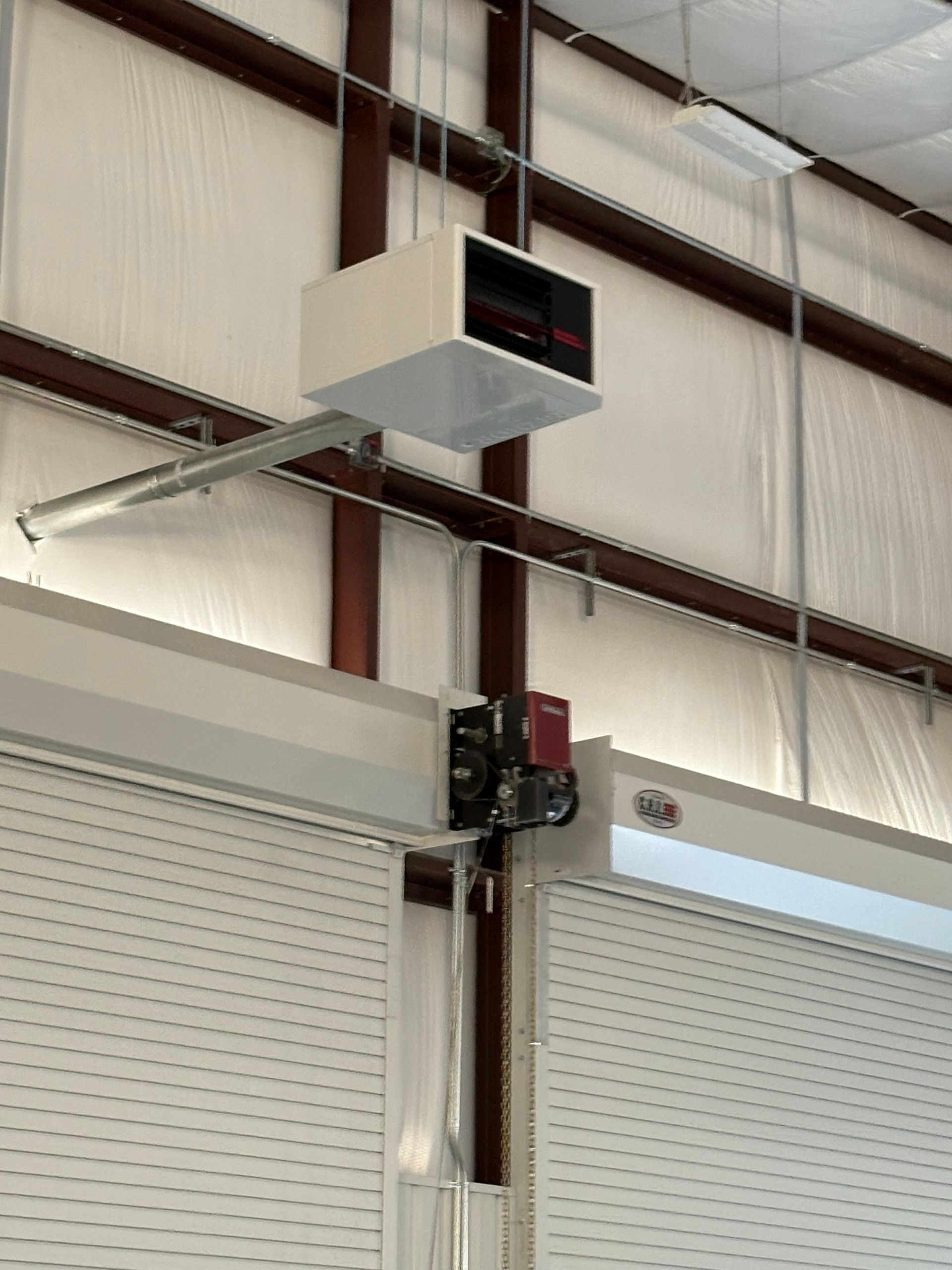 Automated rolling door mechanism and control panel installed in an industrial building.