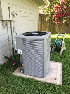 Mitsubishi heat pump unit mounted on a white house exterior with electrical conduit and exhaust pipe.