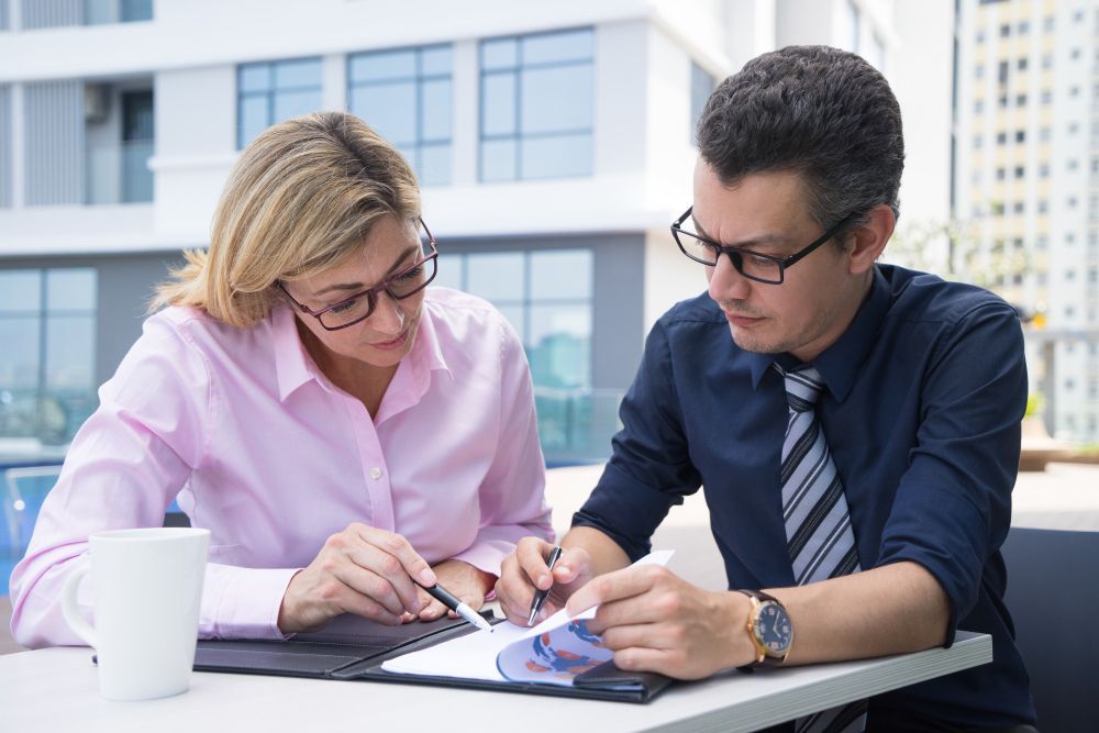 Two business professionals in suits reviewing documents, discussing strategy.
