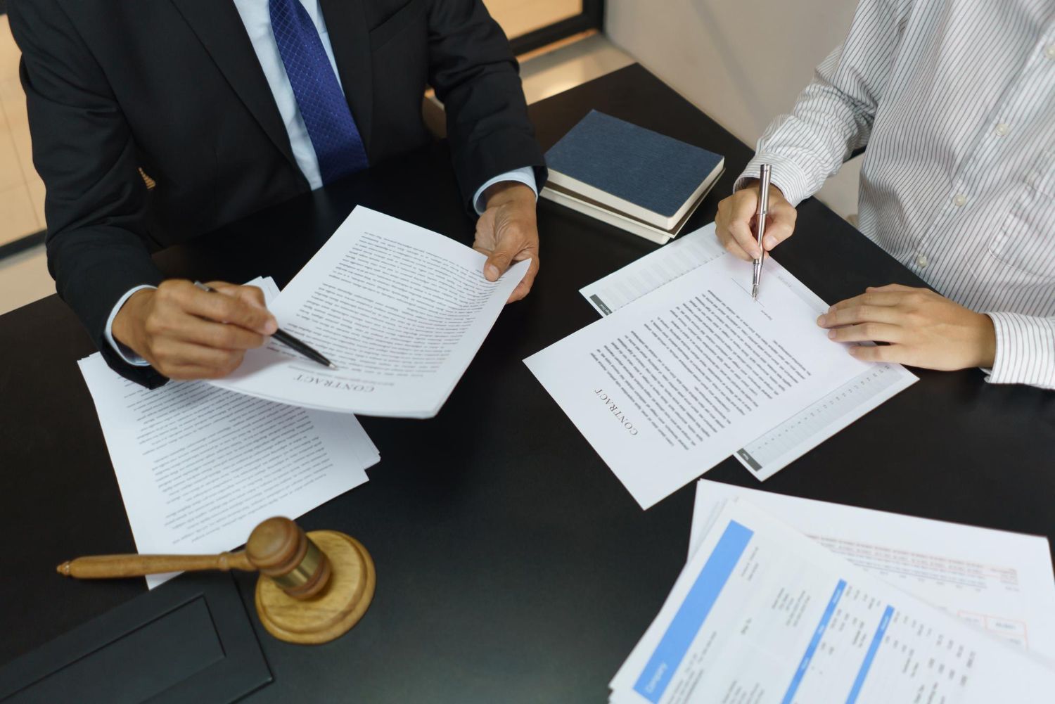 Two business professionals in suits reviewing documents, discussing strategy.