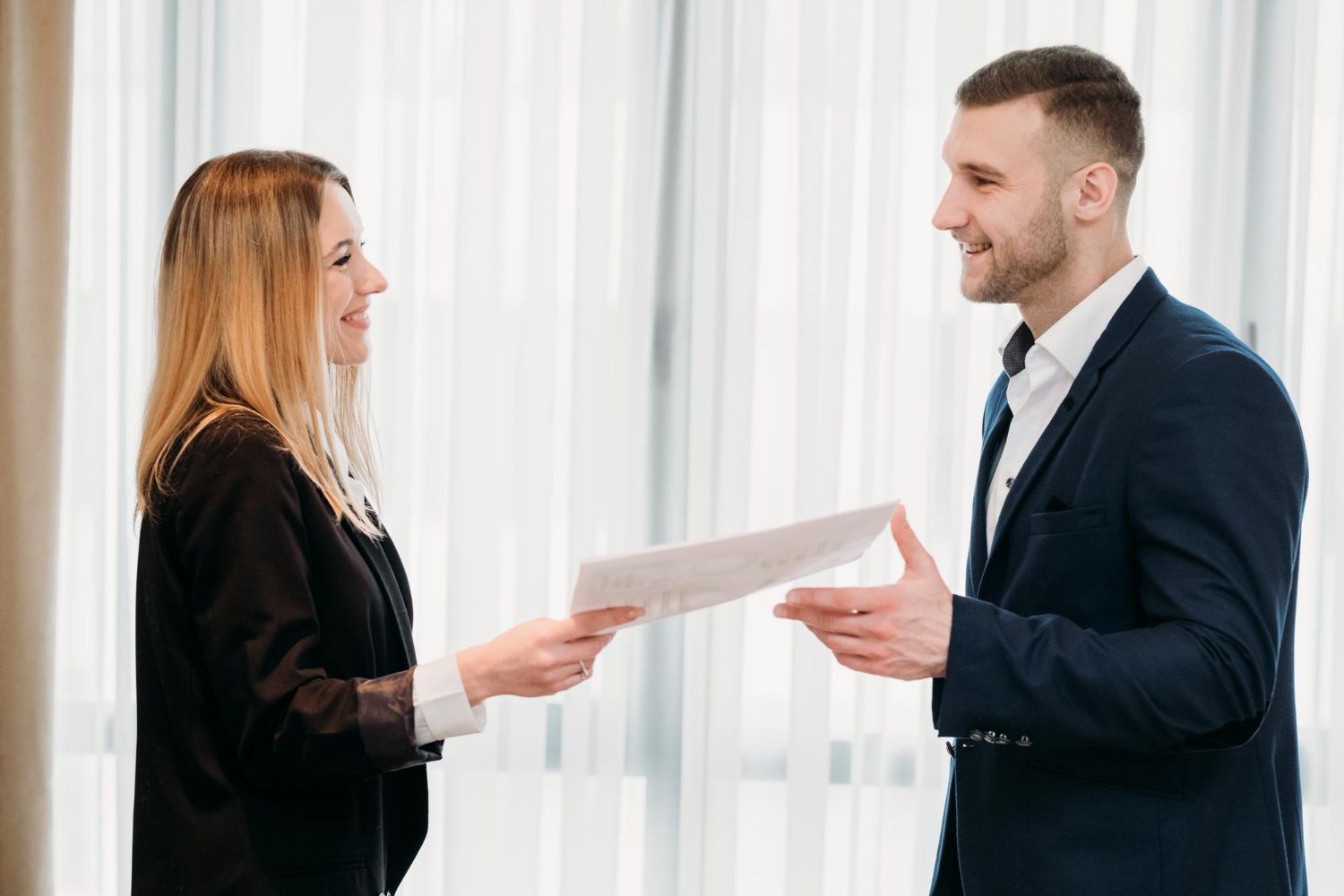 Two business professionals in suits reviewing documents, discussing strategy.