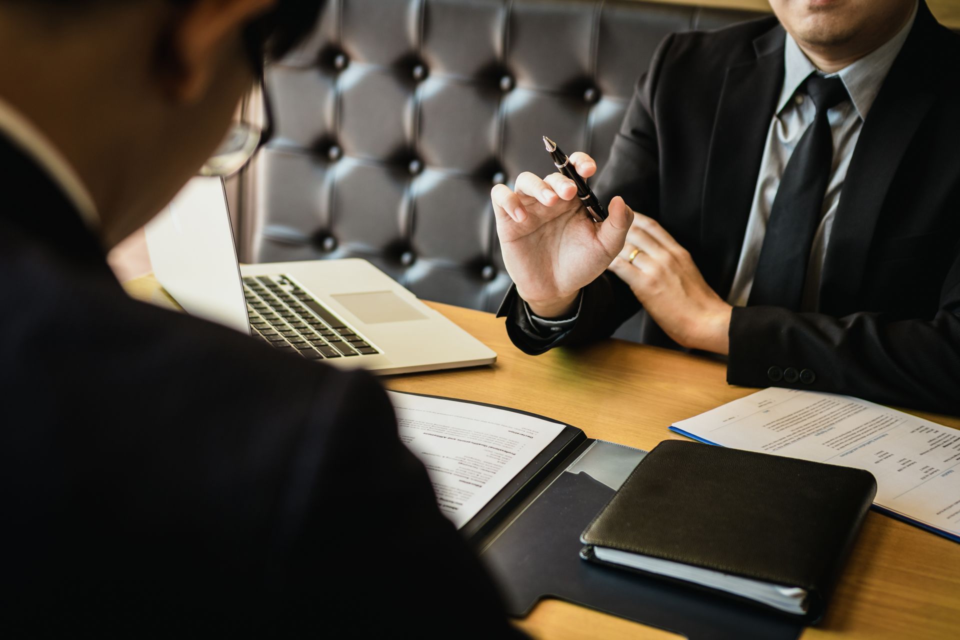 Two business professionals in suits reviewing documents, discussing strategy.