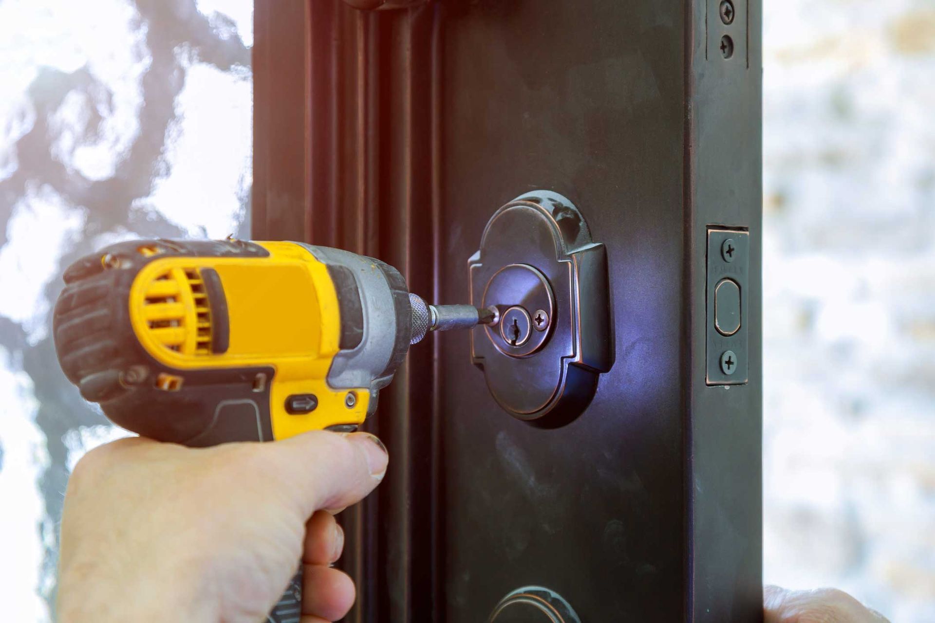 A person is using a drill to fix a door lock.
